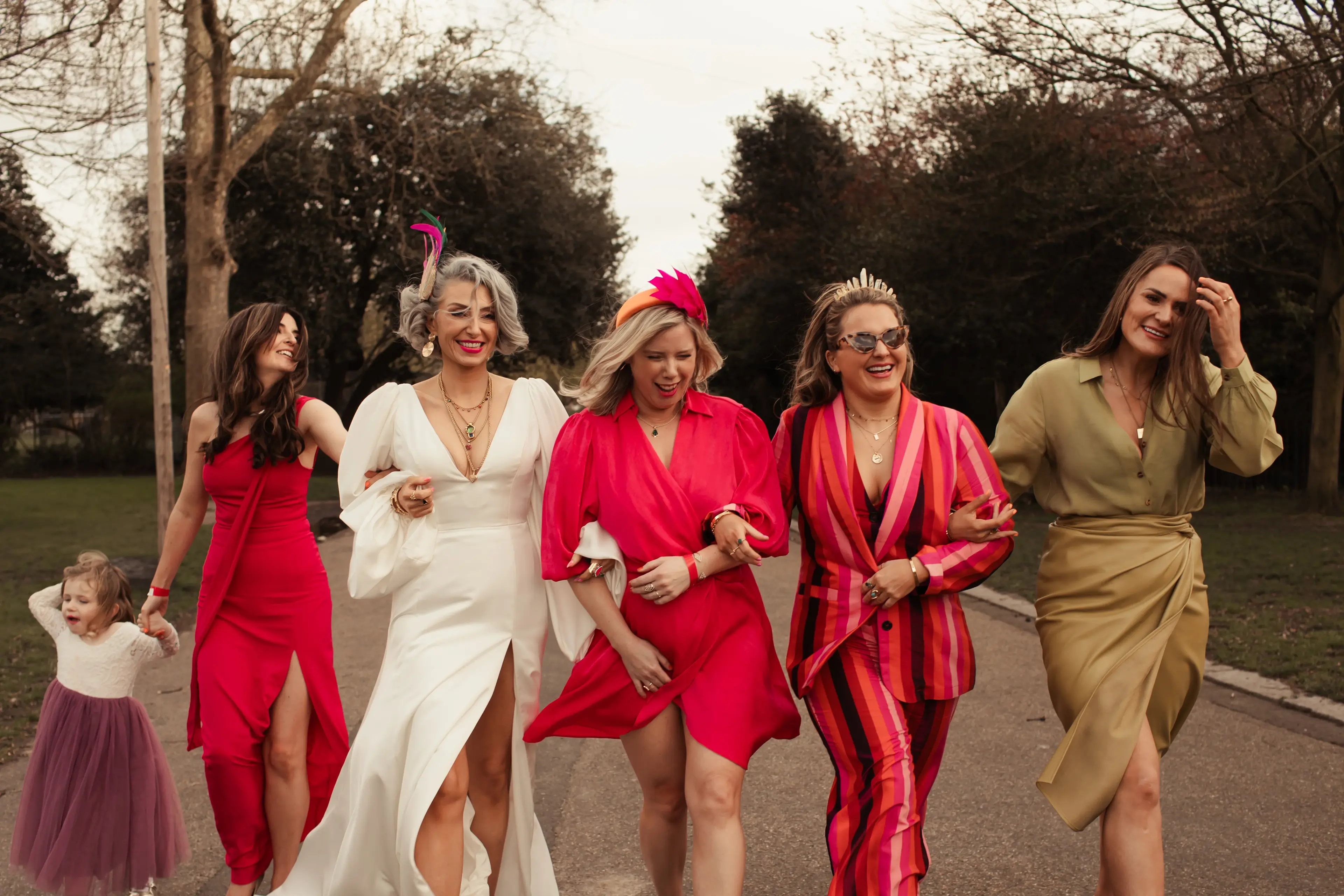 Newly married bride walking through London park with friends