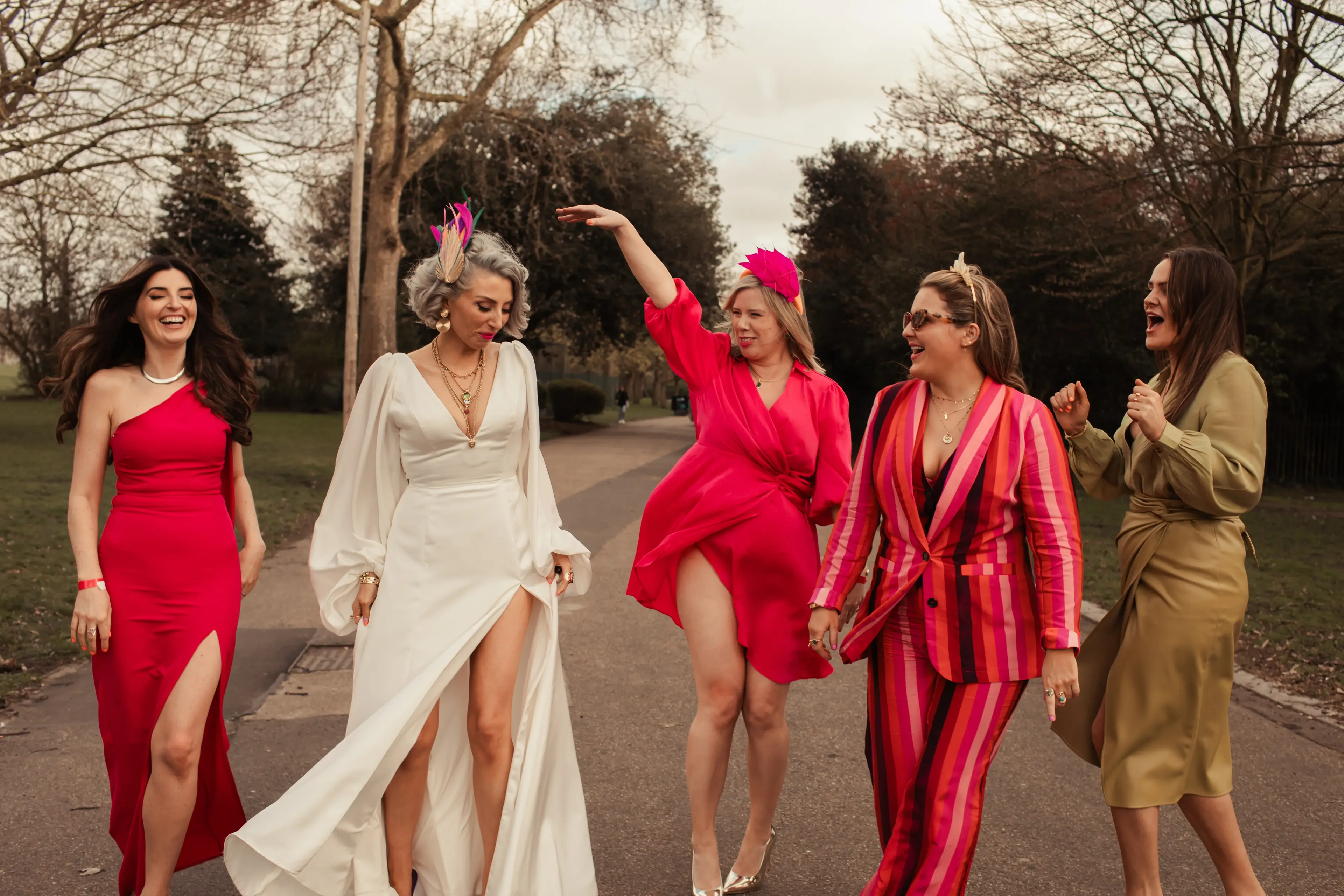 Just married bride walking through a Hackney park with wedding guests