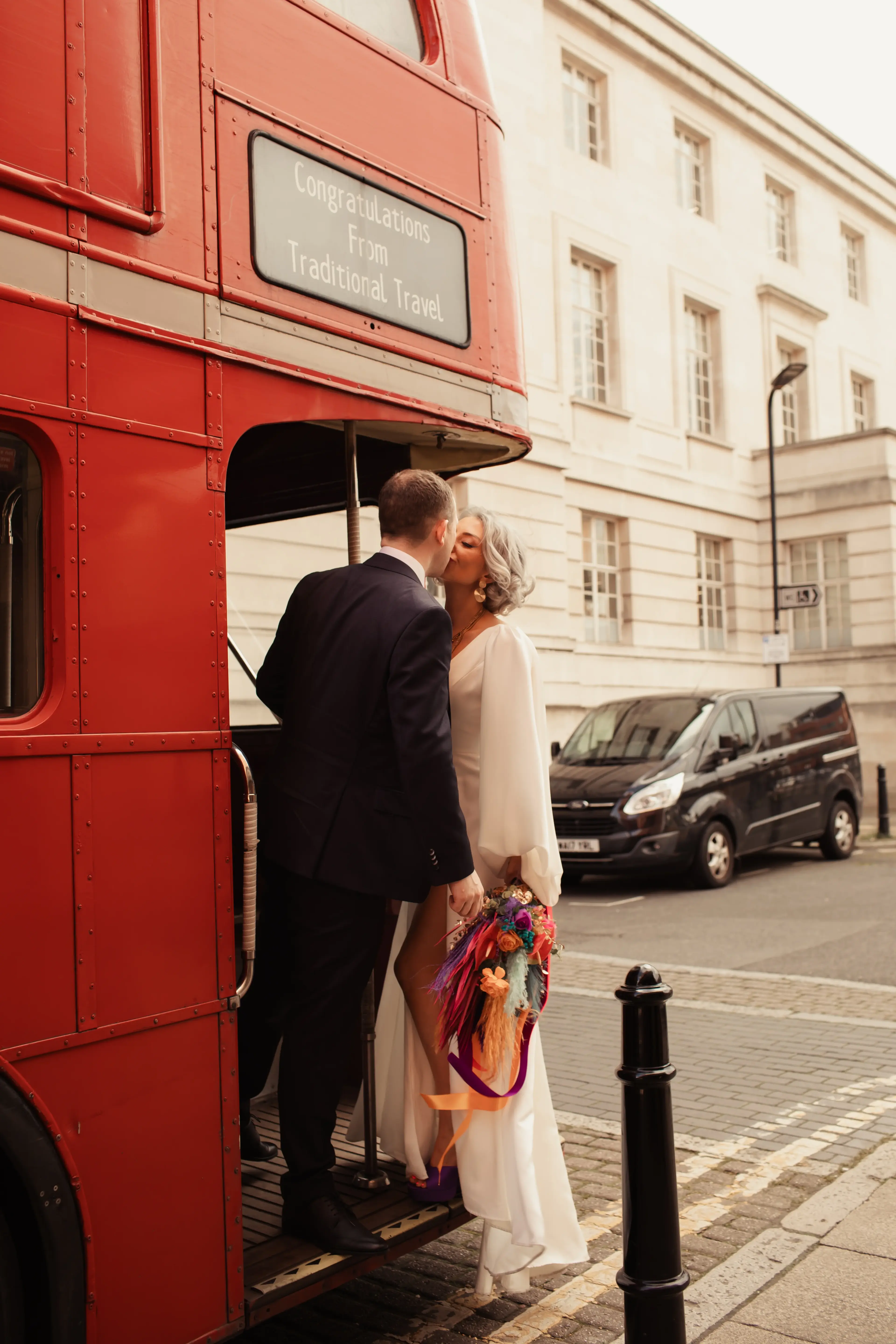 Newlyweds kissing on a red London Bus