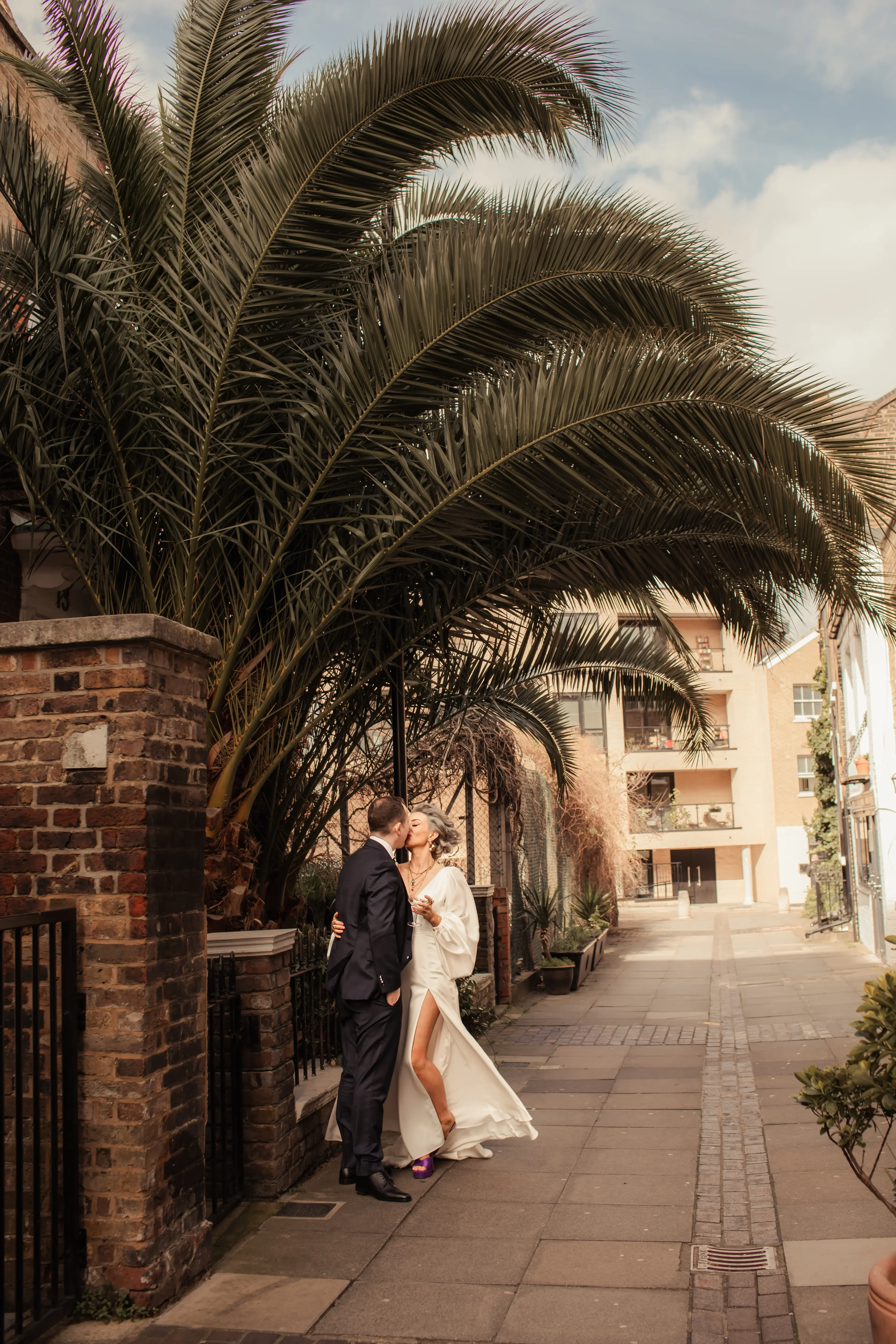 Bride and groom kissing under a leafy tree outside in London