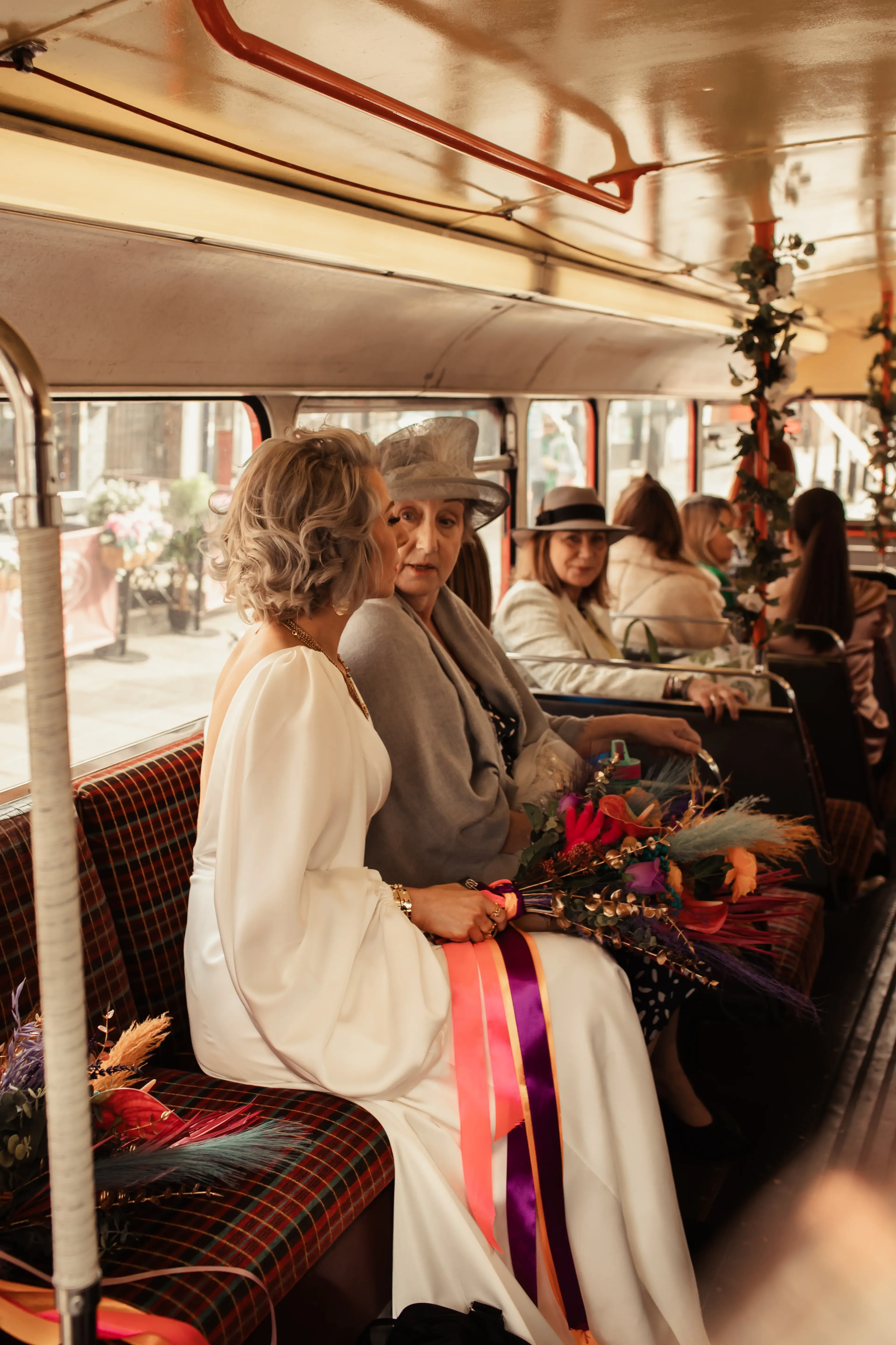 Bride with other guests surrounded by colourful flowers on a traditional red London bus