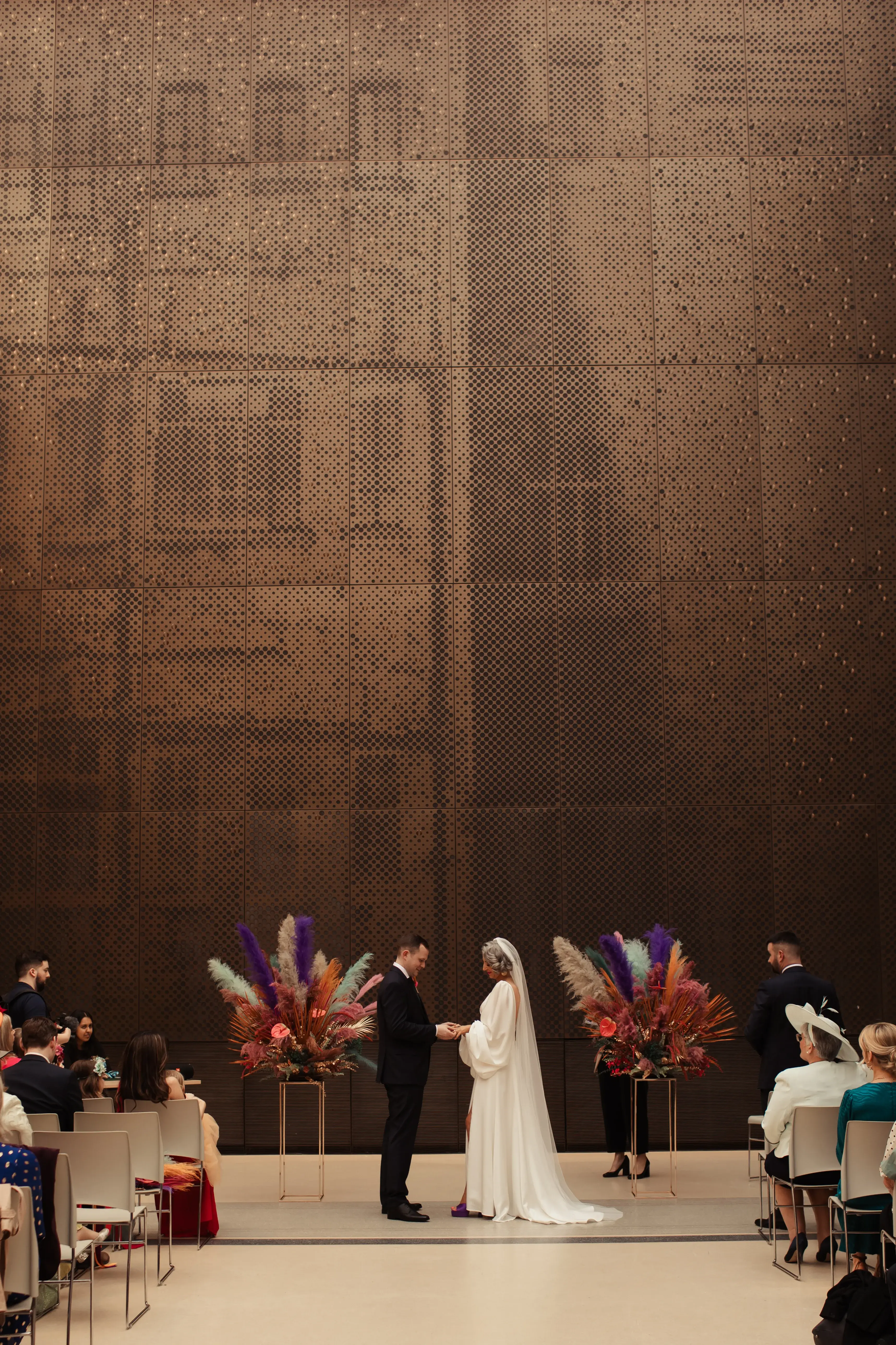 Bride and groom exchanging rings in front of the Hackney Town Hall art deco styling