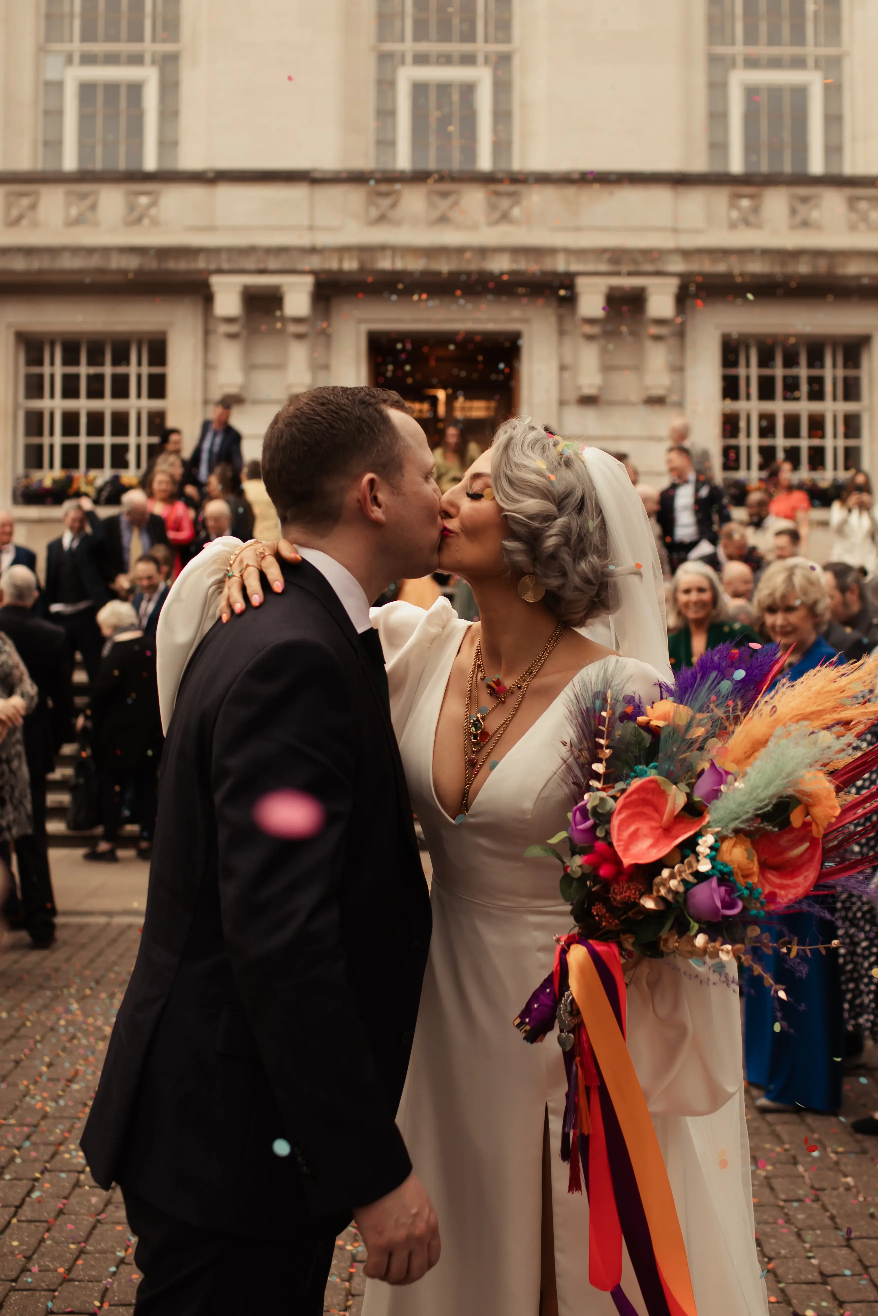 Newly married couple share a kiss under some paper confetti at Hackney Town Hall