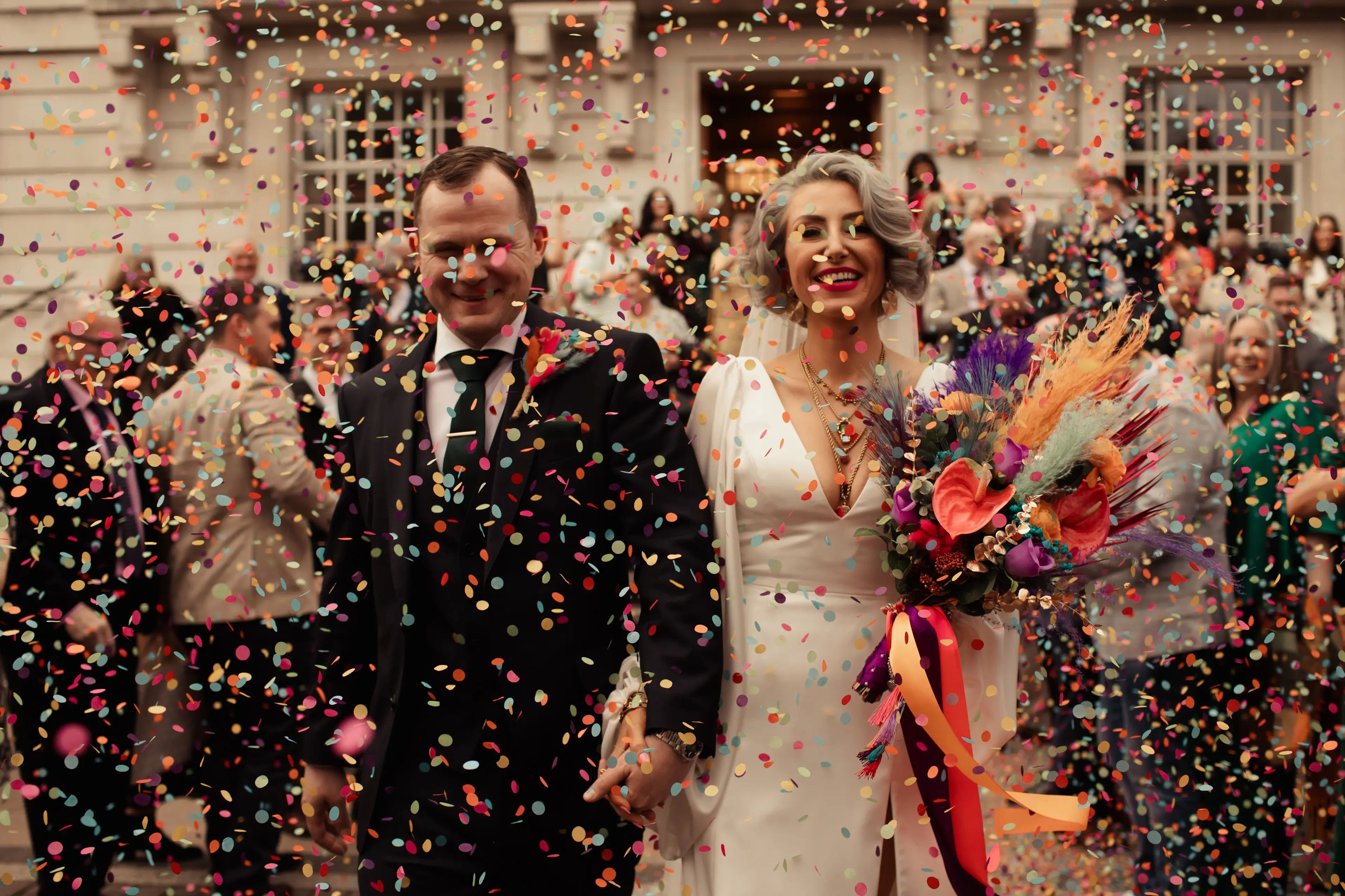 Newlyweds walk through a shower of colourful paper confetti at Hackney Town Hall, London