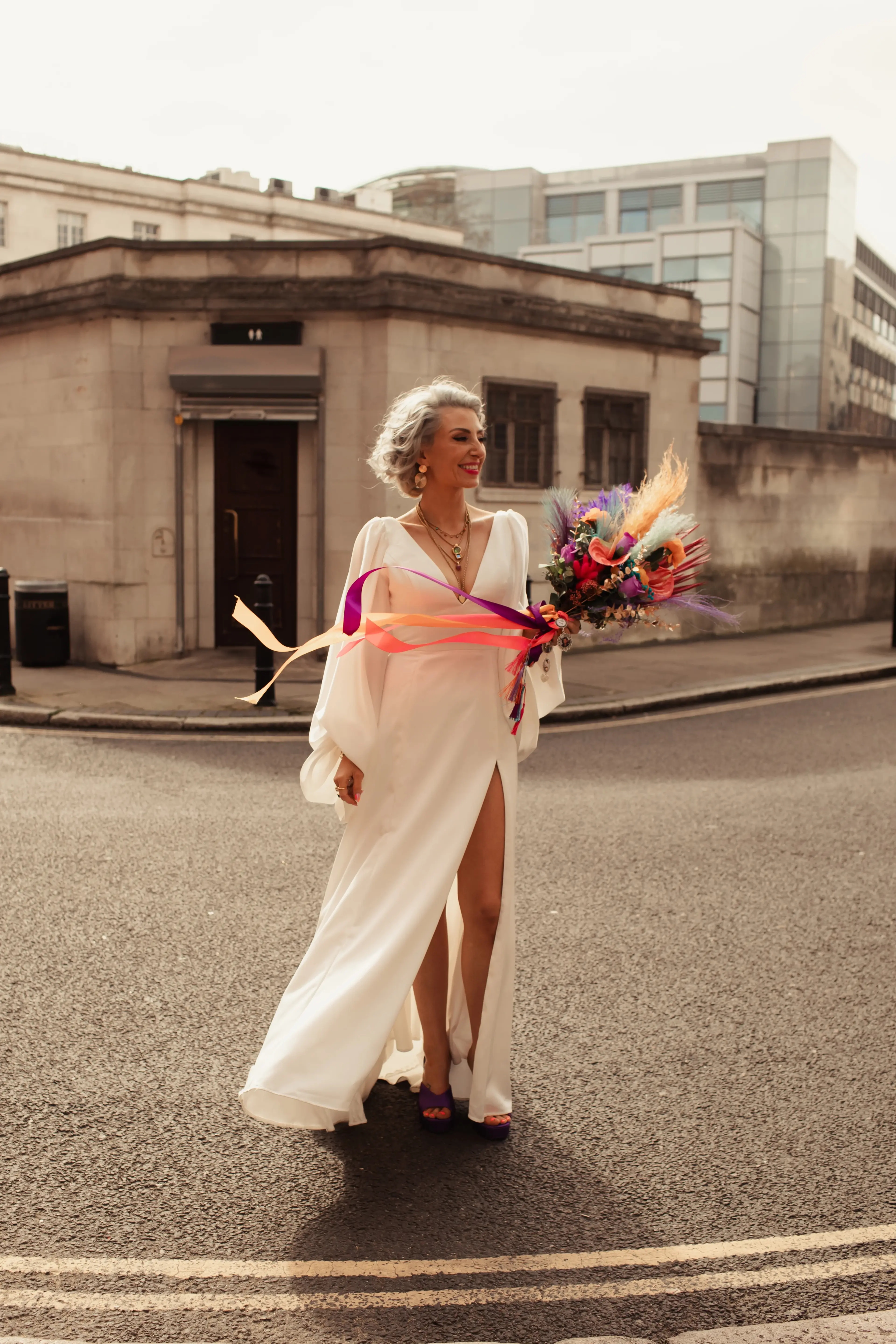 Bride stood out in the wind holding a colourful bouquet in London