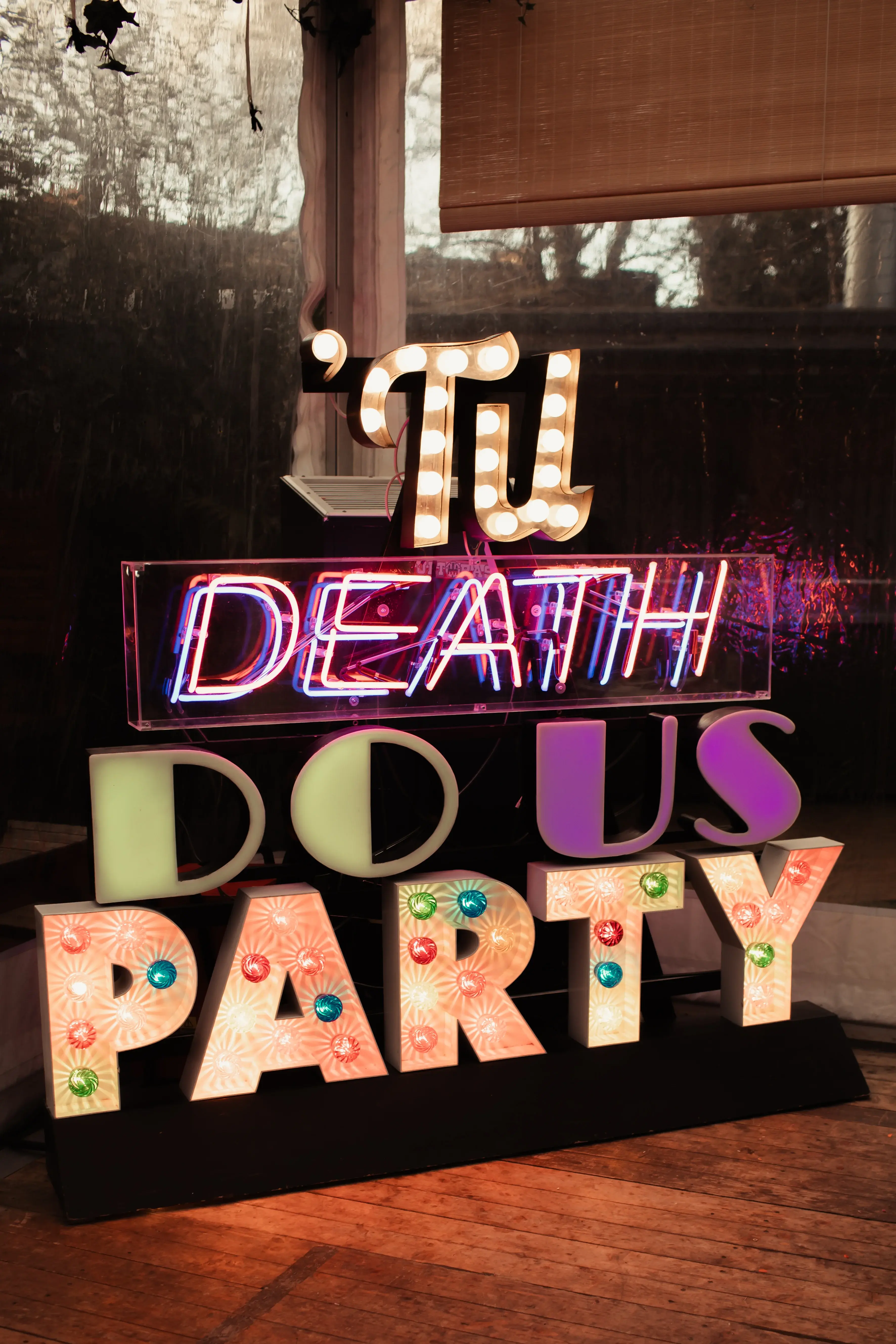 A brightly lit and colourful til death do us party sign at a London pub wedding reception