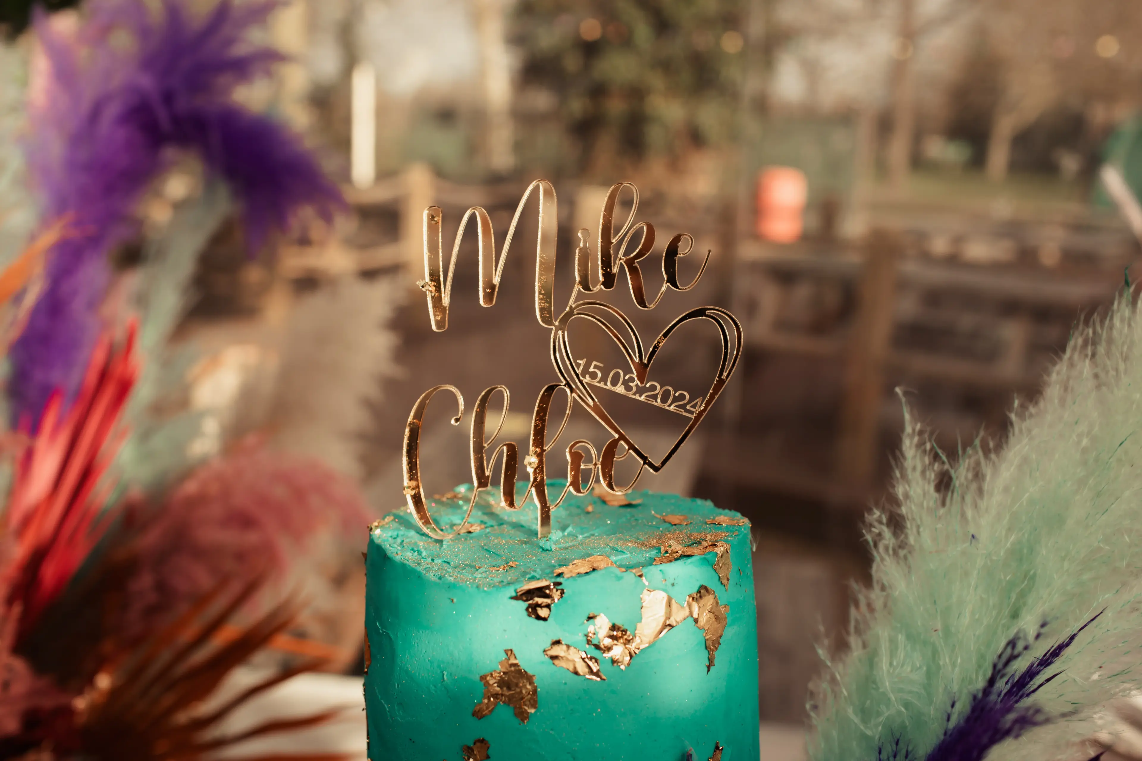 A custom gold wedding cake topper surrounded by floral decorations