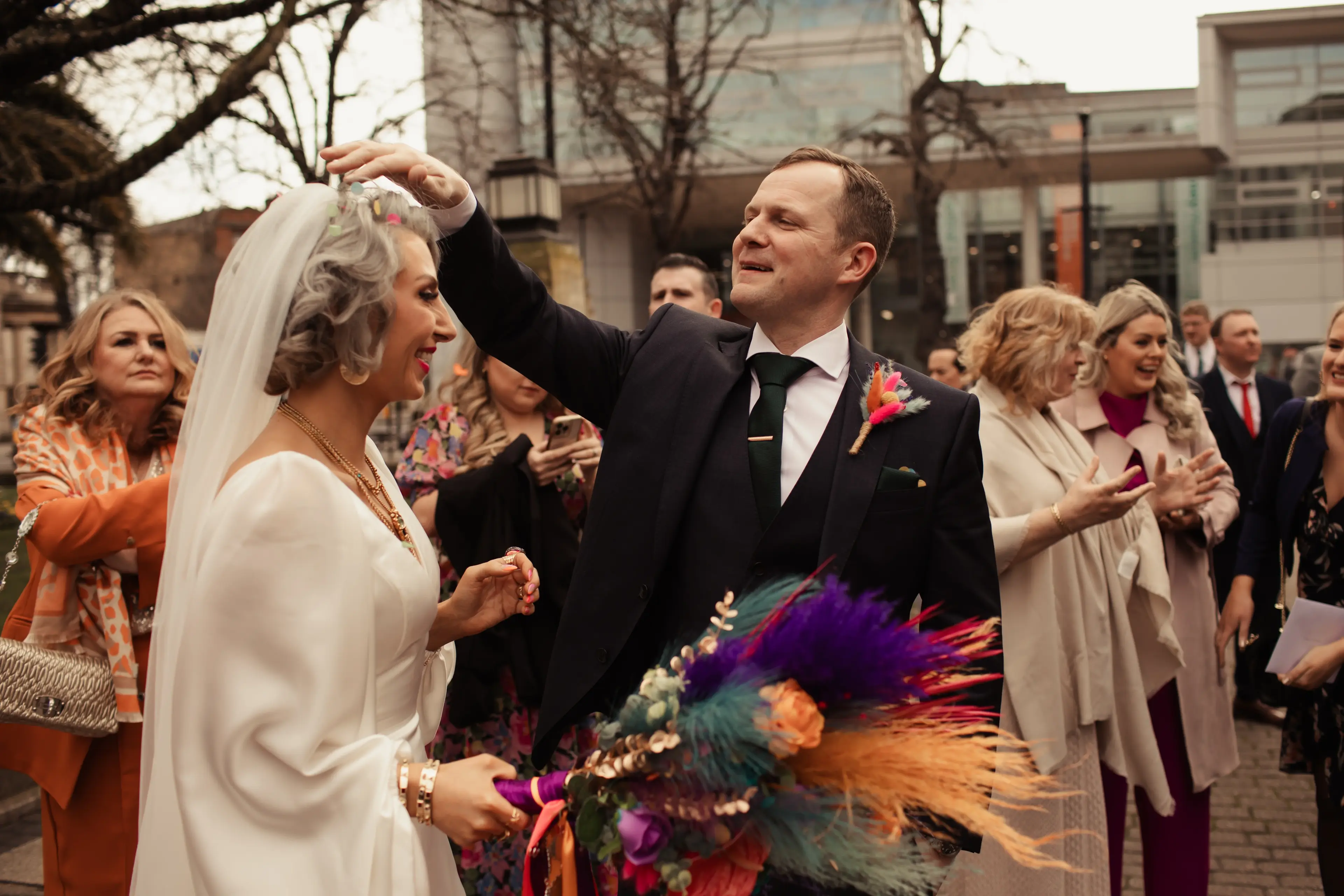 Groom helping his bride fix her veil outside Hackney Town Hall, London