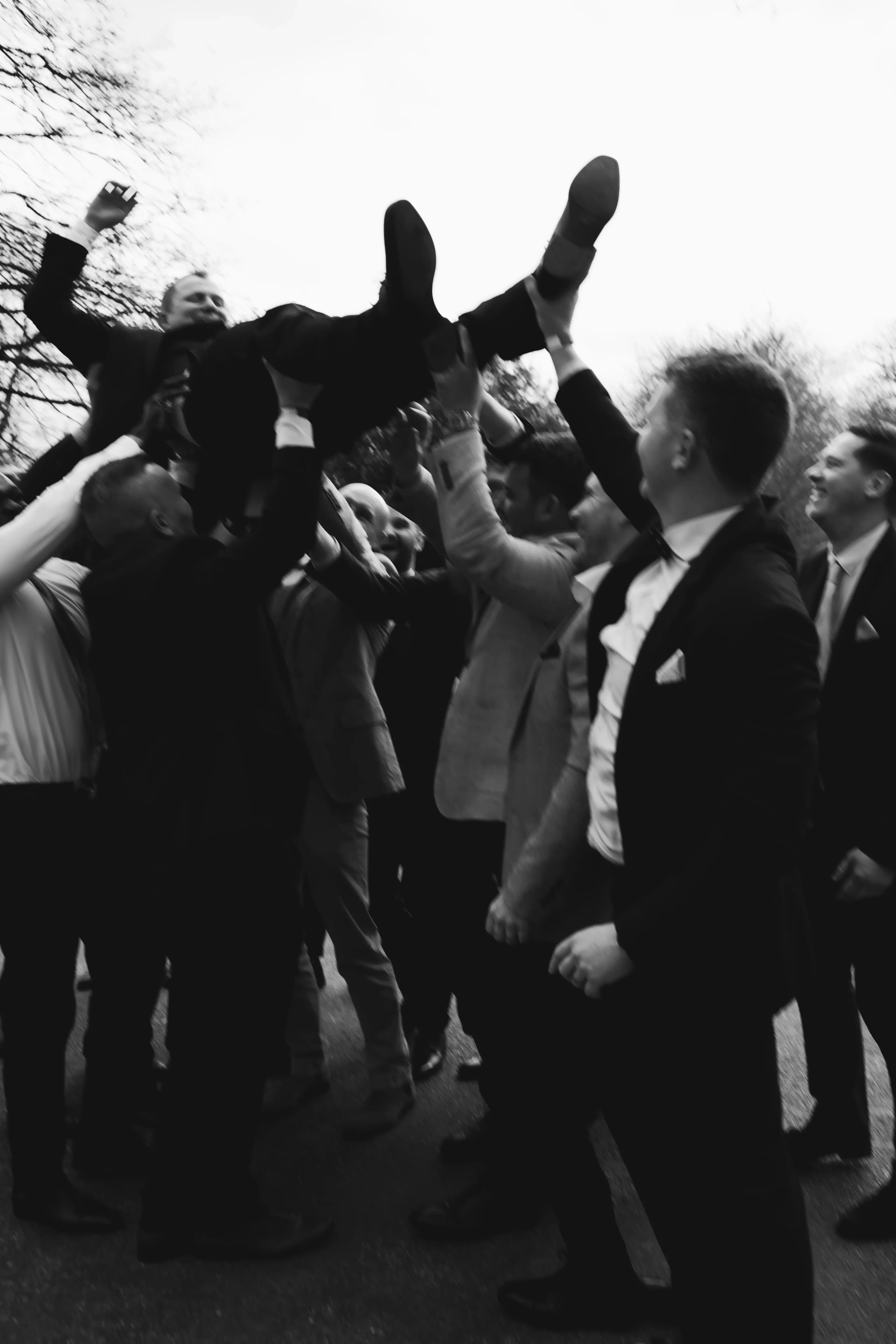 Groom being raised into the air by some wedding guests