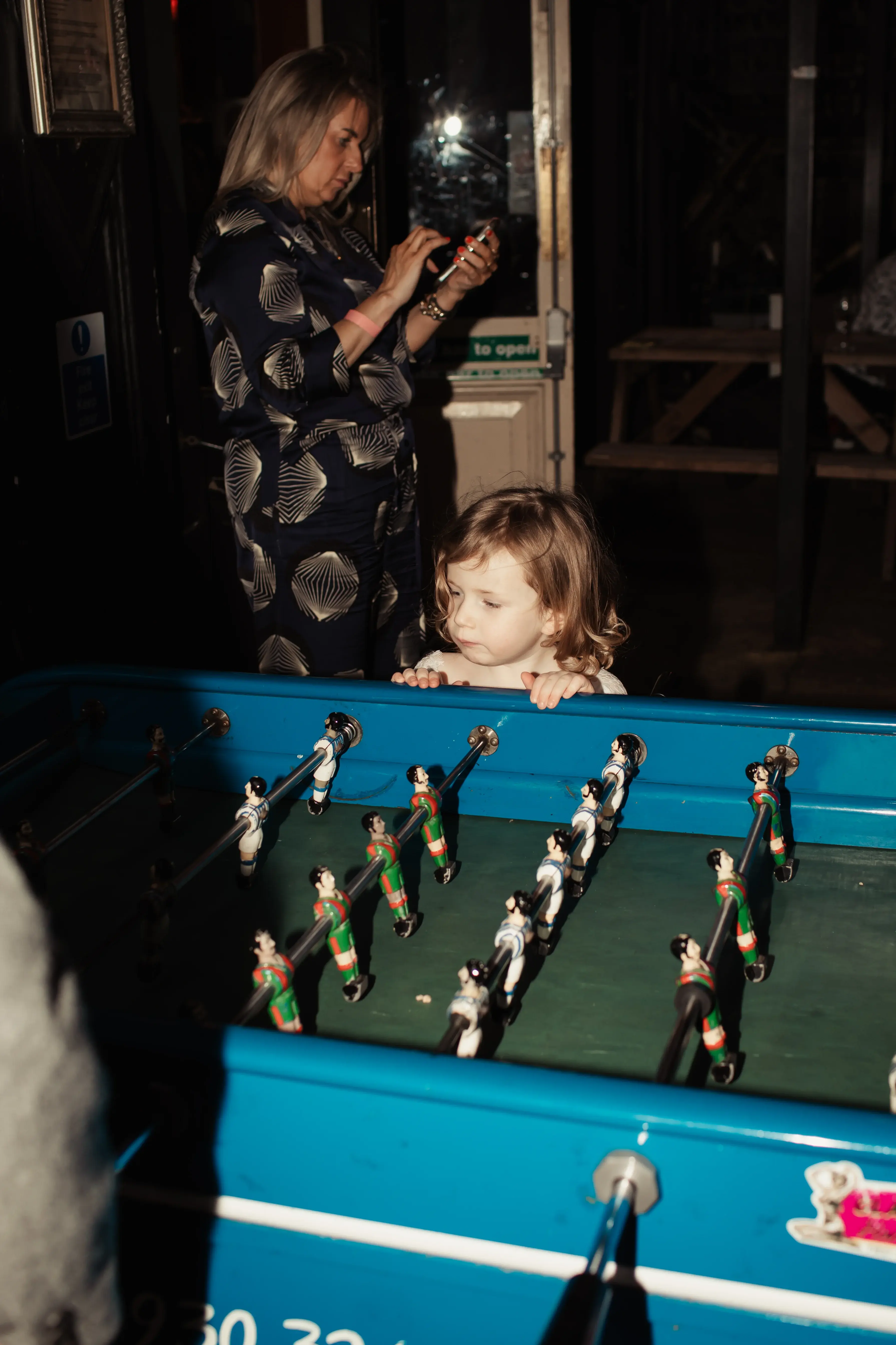 A young wedding guest joining in with some table football at a London pub reception