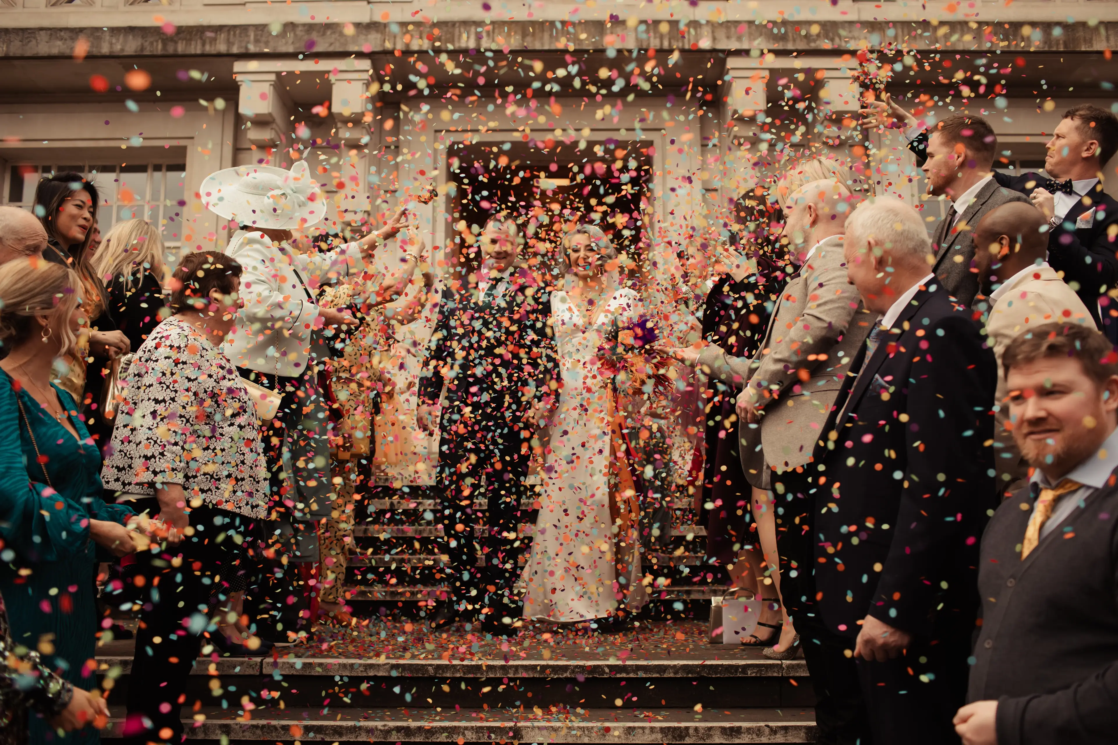 Newly married couple leaving Hackney Town Hall and being showered with colourful paper confetti
